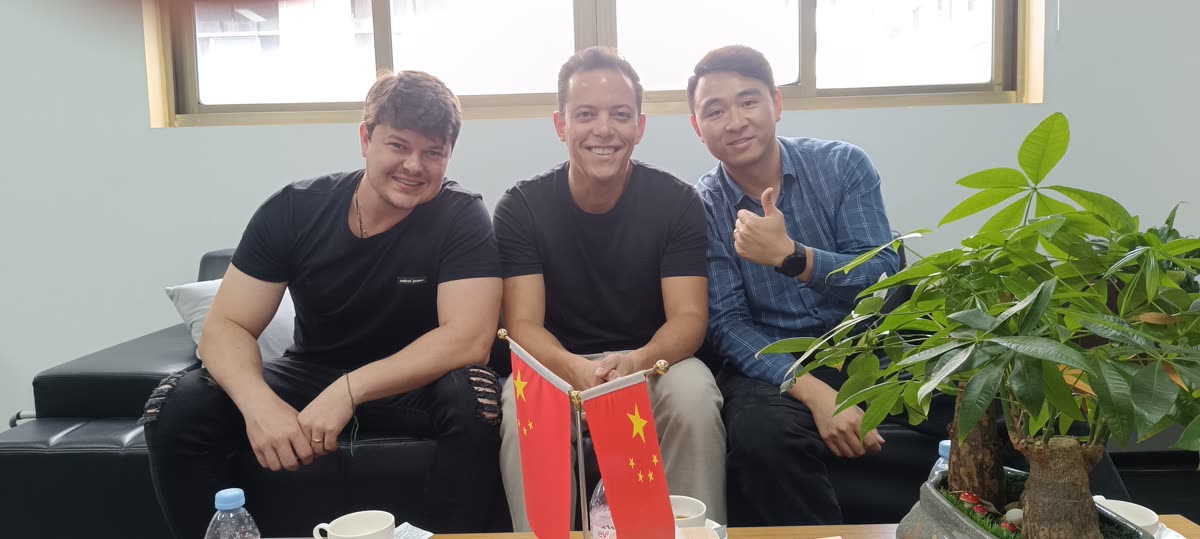 Equipe da China&Co com parceiro chinês no escritório em Chongqing, com as bandeiras do Brasil e da China sobre a mesa